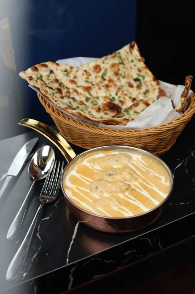Butter chicken with a basket of naan